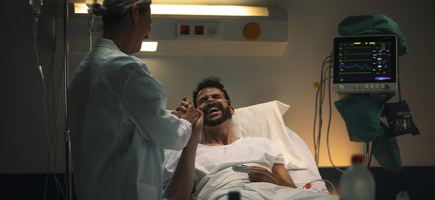 Médica cuidando de um paciente enquanto ambos fazem brincadeiras e sorriem.